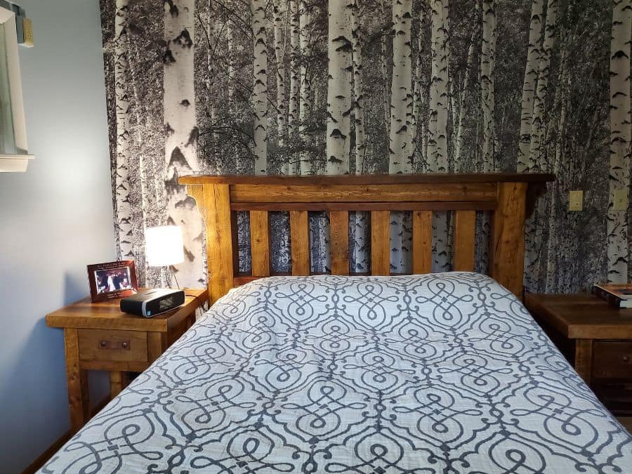 Black and White Birch Tree Wallpaper, as seen on the wall of this rustic bedroom, is a photo wall mural of textured trees in the woods from About Murals.