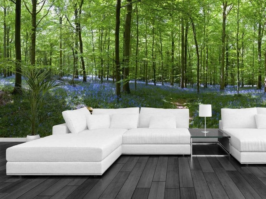 Bluebell Forest Wallpaper, as seen on this wall of this living room, features a bell of blue flowers under green trees from About Murals.