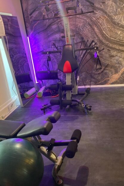 Canadian Shield Swirl Wall Mural, as seen on the wall of this home gym, is a photo wallpaper of a textured faux stone wall from About Murals.