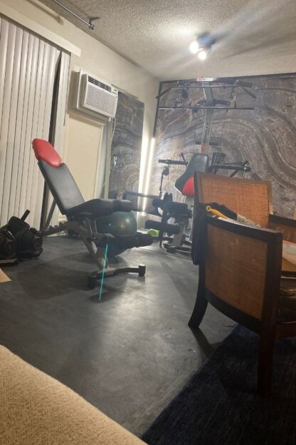 Canadian Shield Swirl Wall Mural, as seen on the wall of this workout area, is a photo wallpaper of a realistic stone wall full of texture from About Murals.