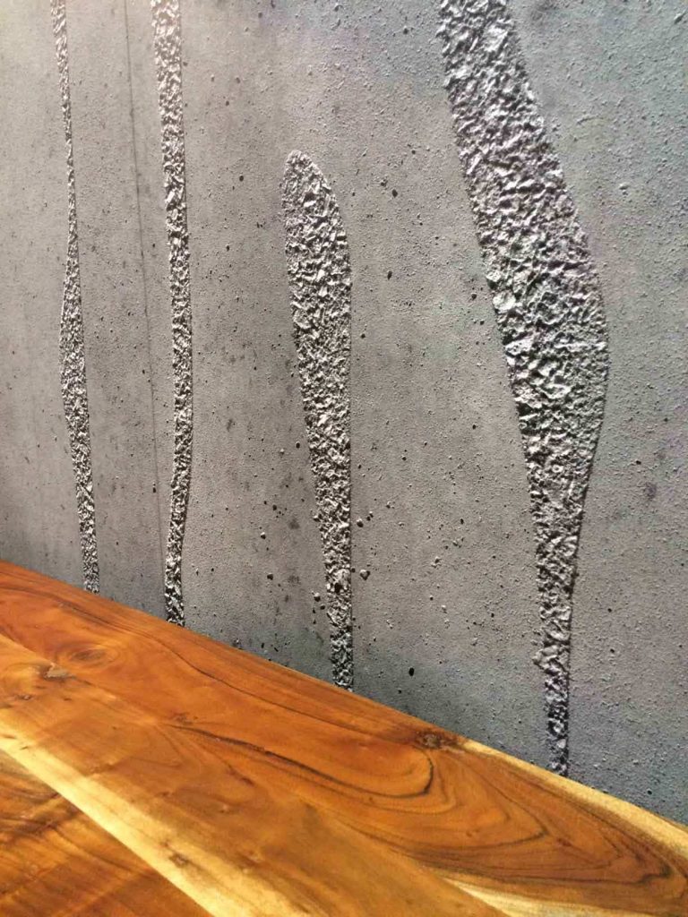 Concrete Waves Wall Mural, as seen over this wooden bar, features swirls of texture in pressed concrete. Concrete wallpaper sold by AboutMurals.ca