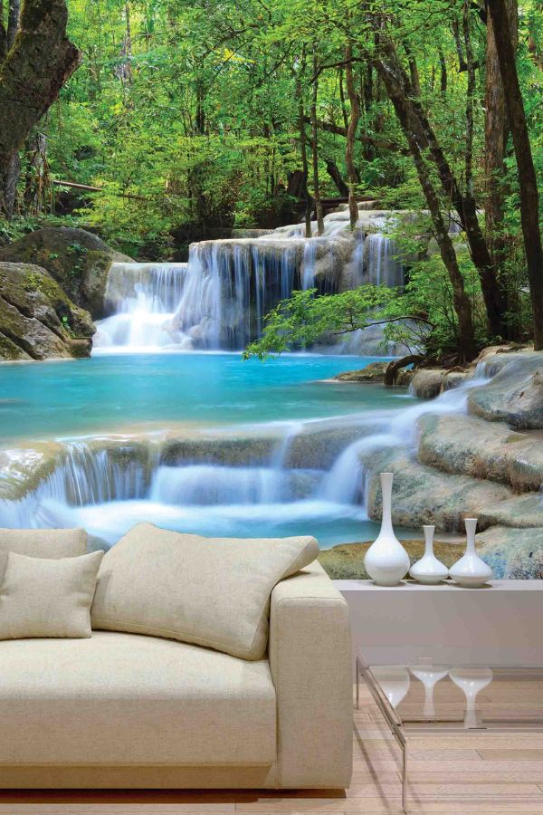 Erawan Waterfalls Wall Mural, as seen on the wall of this living room, is a photo wall mural of blue falls running over large rocks in a Thailand forest from About Murals.