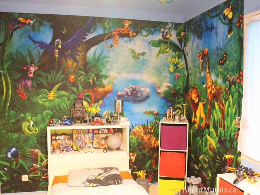 Jungle Wall Mural, as seen in this bedroom, is a children’s wallpaper with happy animals like a lion, giraffe, monkey, hippo, cougar, butterflies and birds in a blue lagoon from About Murals.
