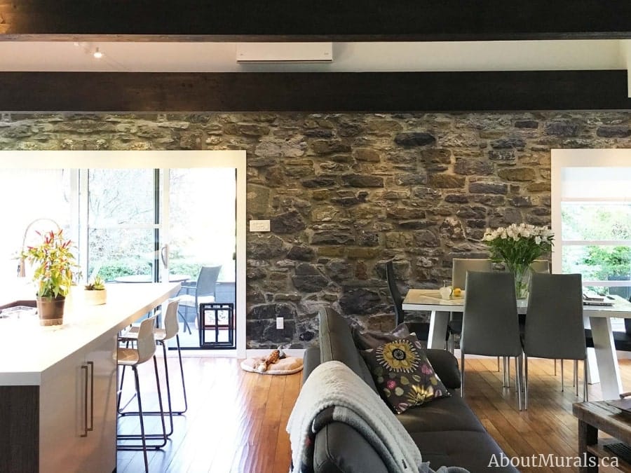 Stone Wall Mural, as seen in this living room, features realistic grey, blue and yellow stacked stones that almost look 3D. Stone wallpaper sold by AboutMurals.ca.