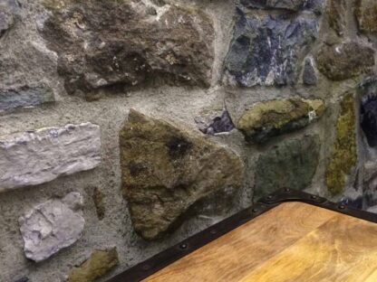 Stone Wall Mural, as seen above this rustic wood shelf, is a photo wallpaper that showcases a realistic texture in its grey, blue and green stacked stones from About Murals.