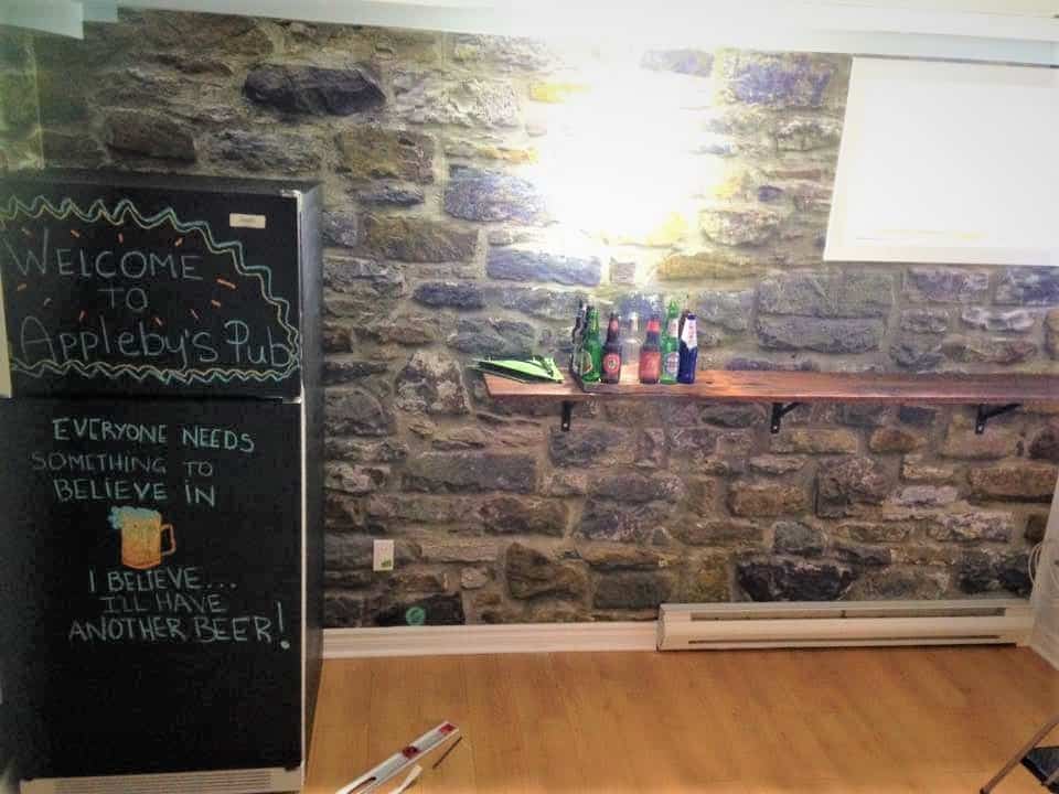 Stone wallpaper, as seen on the wall of this home bar, features grey stones. Faux stone wallpaper from AboutMurals.ca.