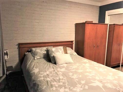White Brick Wallpaper, as seen on the wall of this bedroom, features white painted brick. Brick wallpaper sold by AboutMurals.ca.