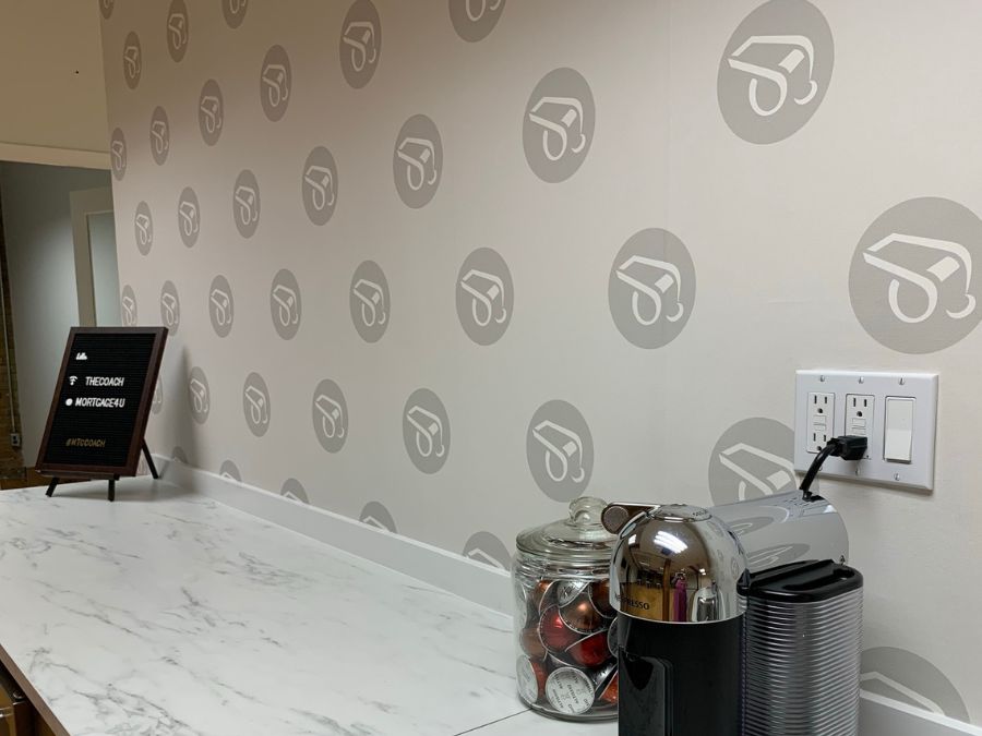 Custom Made Wallpaper, as seen on the wall of this mortgage broker office, features repeating logos of whistles from About Murals.
