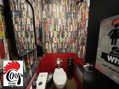 Custom Wallpaper, as seen on the wall of the Coop Wicked Chicken Restaurant, of VHS tapes from the 90s in a bathroom from About Murals.