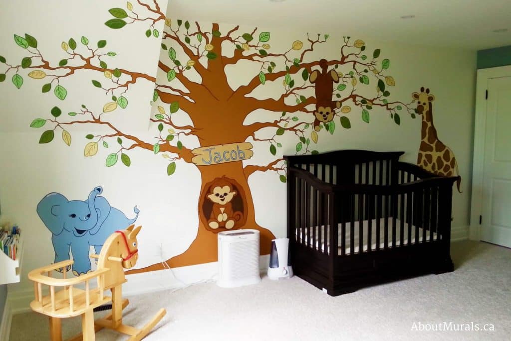 A safari tree mural featuring a tree with an elephant, giraffe and monkeys over a baby crib