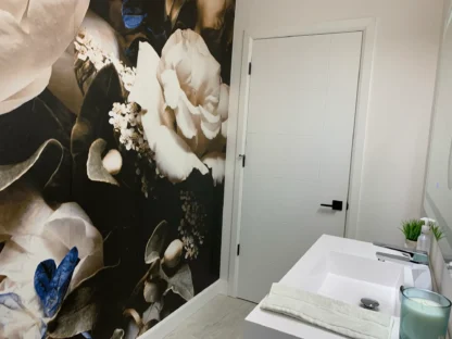 Black Floral Wallpaper, as seen on the wall of this bathroom, is a humidity resistant wallpaper that features oversized rose and peony flowers on a dark background from About Murals.