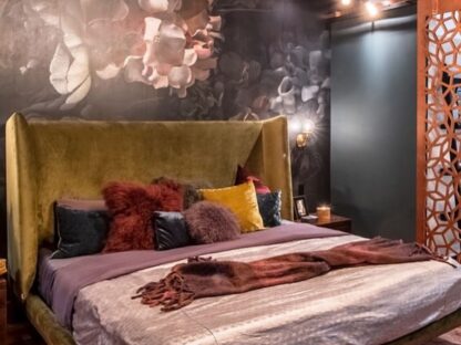 Dark Floral Wallpaper, as seen on the wall of this dark bedroom with pink, purple and yellow bedding, is a wall mural of large peony flowers full of texture on a black background from About Murals.