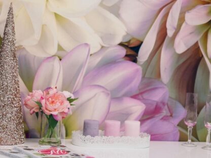 A close-up view of a pink flower wallpaper, on the wall behind a table with a magazine and candles, from About Murals.
