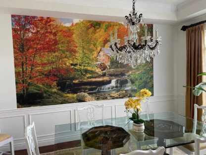 Watermill Wallpaper, as seen on the wall of this natural feeling dining room, is a photo wallpaper of a watermill in a red and yellow fall forest from About Murals.