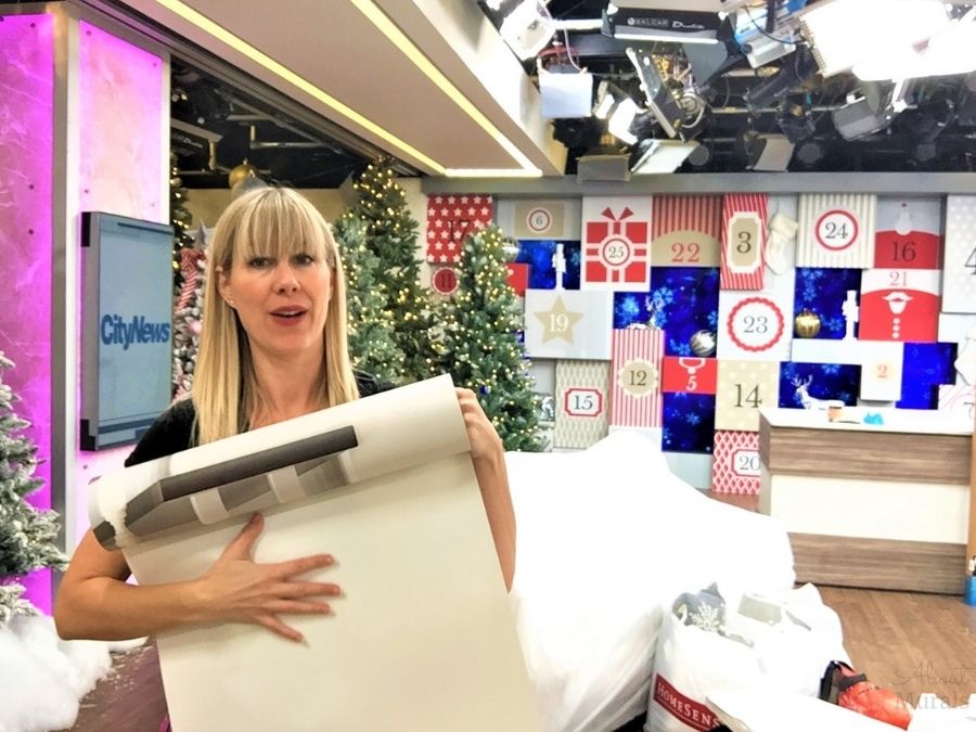 Adrienne explains what easy wallpaper is on set at Cityline while holding a wallpaper panel
