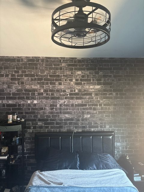 Black Brick Wallpaper, as seen on the wall of a bedroom, is a photo mural that captures all the texture of the modern brick from About Murals.