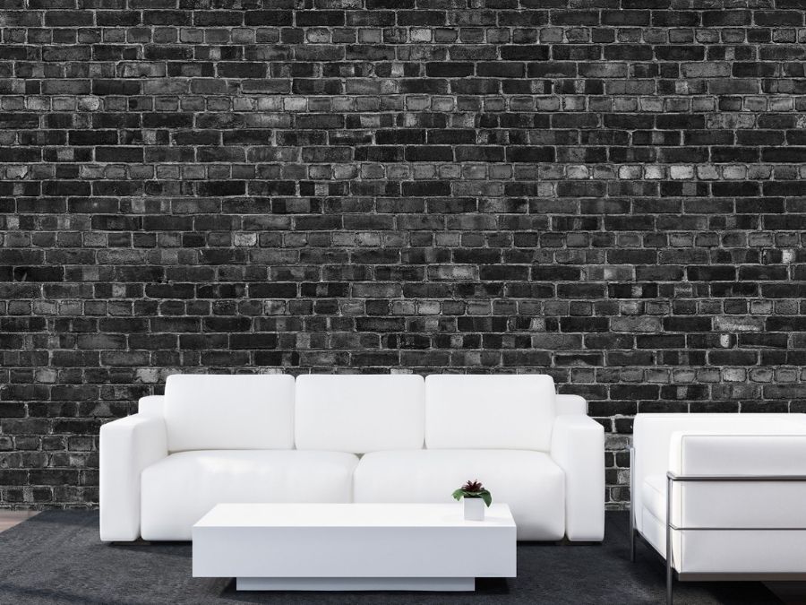 Black Brick Wallpaper, as seen on the wall of this living room with a white couch, is a high resolution photo mural of textured black bricks from About Murals.