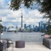 Toronto Wallpaper, as seen on the wall of this living room, features skyline views of skyscrapers, the CN Tower and The Rogers Centre reflected in Lake Ontario from About Murals.