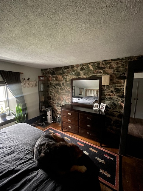Field Stone Wallpaper, as seen on the wall of this rustic bedroom, is a wall mural with textured stones from About Murals