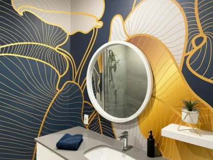 Philodendron Wallpaper, as seen on the wall of this modern bathroom, is a tropical leaf mural with blue, gold and grey leaves from About Murals.