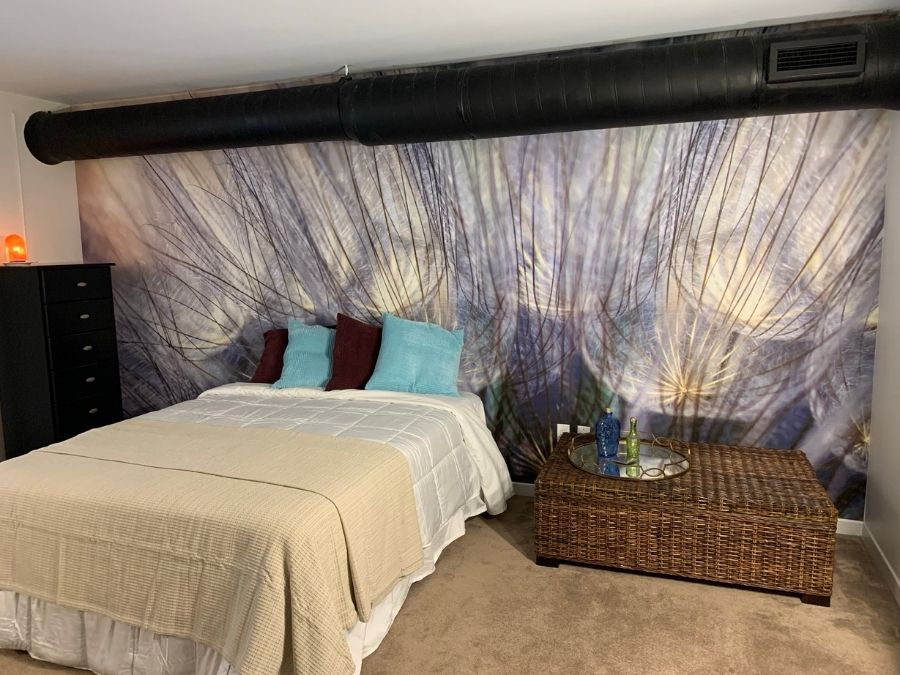 Purple Blue Dandelion Wallpaper, as seen on the wall of this loft bedroom, is a photo mural of a large flower up close from About Murals.