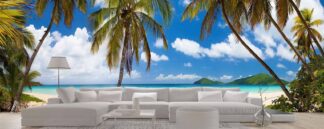 Beautiful Beach Wallpaper, as seen on the wall of this living room, is a photo mural of a panoramic beach with palm trees, blue ocean, white sand and tropical islands in the distance from About Murals.