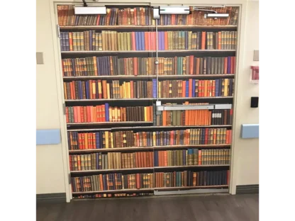 Bookshelf Wallpaper, as seen on an exit door in a care home, is a mural with old colourful books on shelves from About Murals