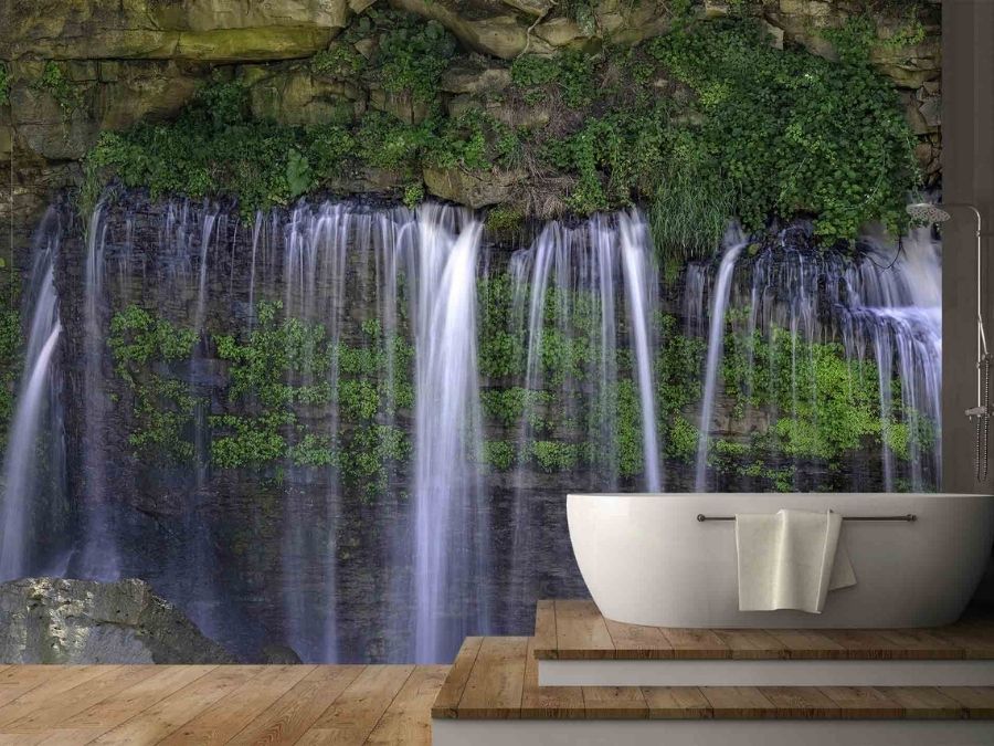 Forest Waterfall Wallpaper, as seen on the wall of this bathroom, is a high resolution photo mural of water showering through a rock crevasse over green foliage from About Murals.