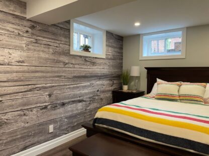 Grey Wood Wallpaper, as seen on the wall of this bedroom, is a high quality photo mural of grey vertical wooden planks with grain and knots that create a textured look from About Murals.