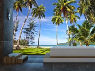 Palm Trees Beach Wallpaper, as seen on the wall of this ocean themed bathroom, is a photo mural of tropical trees over green grass leading to a white beach and turquoise ocean from About Murals.