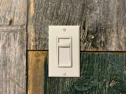 Rustic Wood Wallpaper, as seen on a wall behind a plug, is a photo mural with grey, green and red wood planks from About Murals