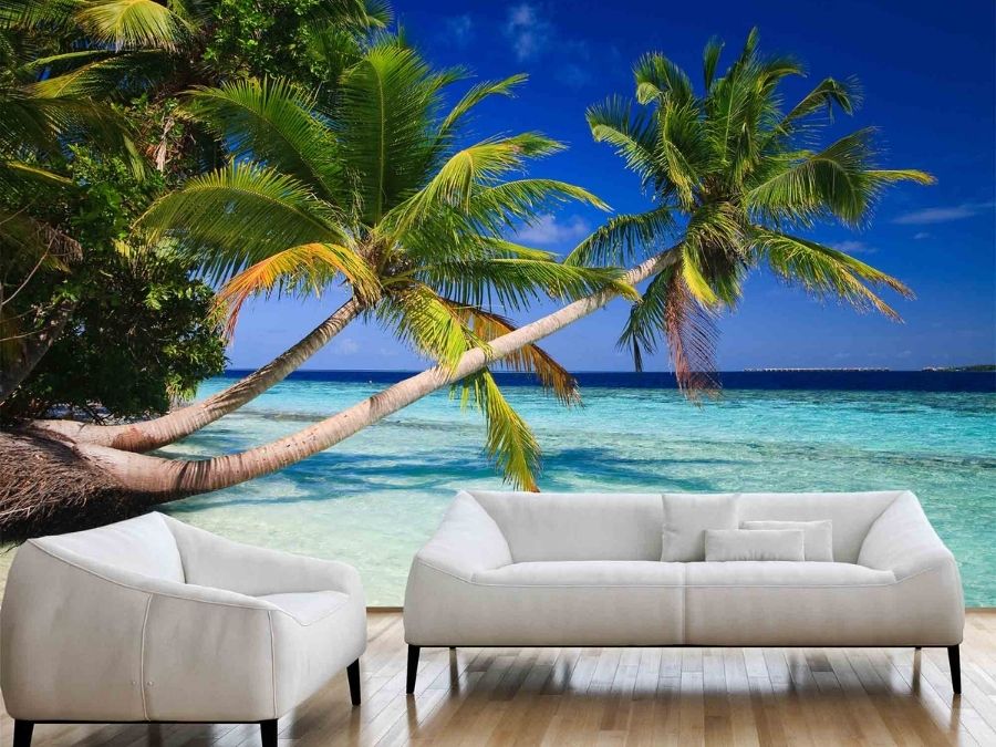 Tropical Beach Wallpaper, as seen on the wall of this living room, is a photo mural of palm trees hanging over a turquoise ocean on a tropical island from About Murals.