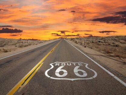 Route 66 Wallpaper is a wall mural of the cool logo painted on the Mother Road under a setting sun in the desert from About Murals.