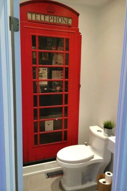 Phone Booth Wallpaper, as seen on the wall of this restroom, is a photo mural of a vintage red English telephone booth from About Murals.