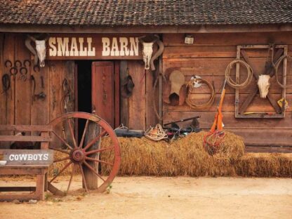Wild West Wallpaper is a wall mural of a wood barn in the desert with a bull skull, horse saddle, rope and haystacks from About Murals.