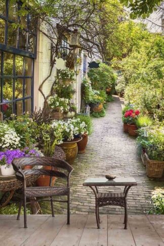 Europe Street Wallpaper, as seen on the wall of this living room, is a photo mural of a cobblestone street filled with potted flowers from About Murals.