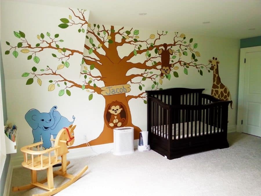 A painted mural in Waterdown, ON of an elephant, monkey and giraffe under a tree in a baby nursery by muralist Adrienne Scanlan of About Murals.