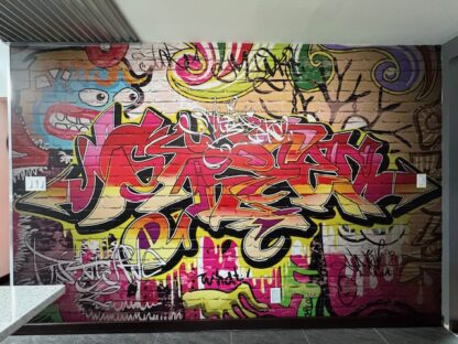 Graffiti Brick Wallpaper, as seen on the wall of this kitchen, is a mural featuring a fun and colourful spray paint look on top of white brick from About Murals.