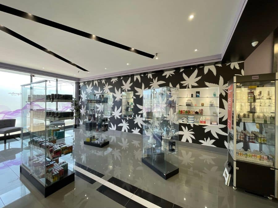 Cannabis Store Wallpaper, as seen on the wall of Signature Vape, is a custom mural of white cannabis leaves on a black background from About Murals.