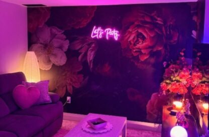 Dutch Floral Wallpaper, as seen on the wall of this room backlit with a purple neon light, is a floral mural with a dark background from About Murals