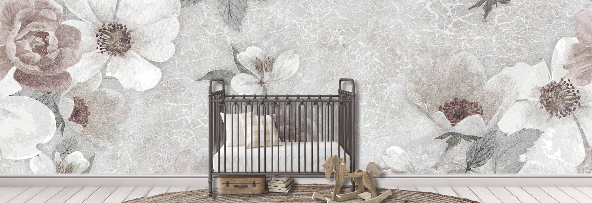 A children’s floral wallpaper, as seen on the wall of this baby nursery, is a wall mural featuring soft, elegant roses on a muted grey background from About Murals.