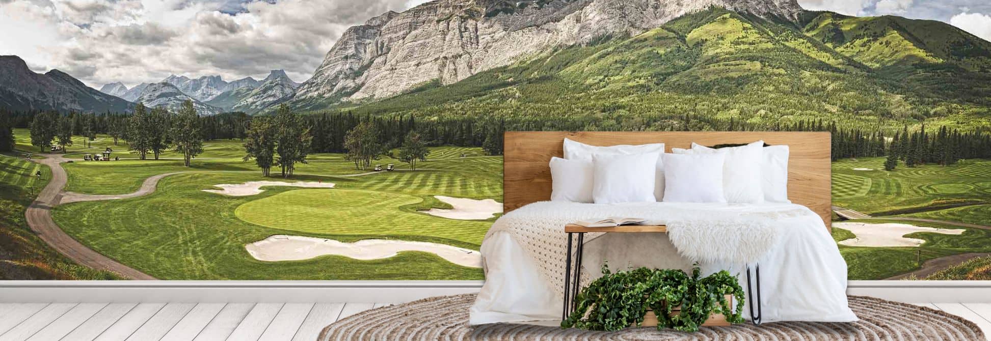 Golf wallpaper, as seen on the wall of this bedroom, is a photo wall mural of a golf course with lush greens surrounded by mountains and trees from About Murals.