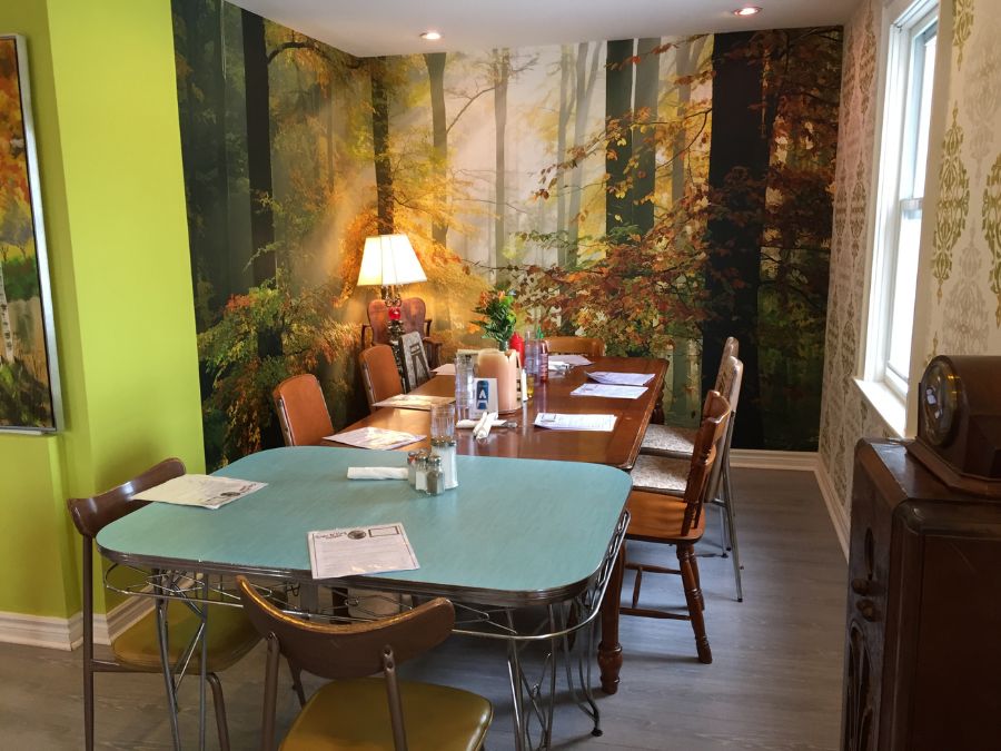 50s diner wallpaper featuring an autumn forest design behind mid century modern table and chairs from About Murals