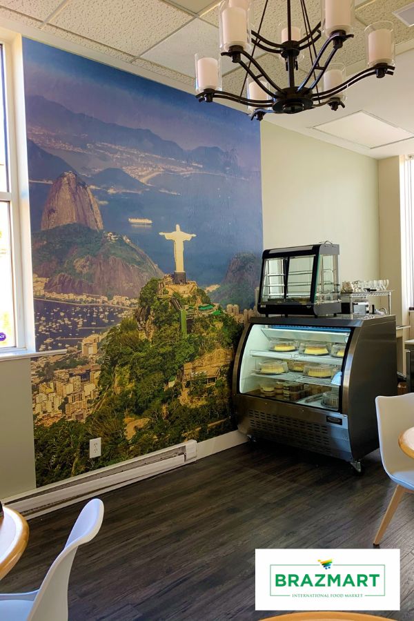 A cafe mural on the wall behind a small pastry fridge at a Brazilian cafe in St. Catharines, ON, Canada by About Murals.