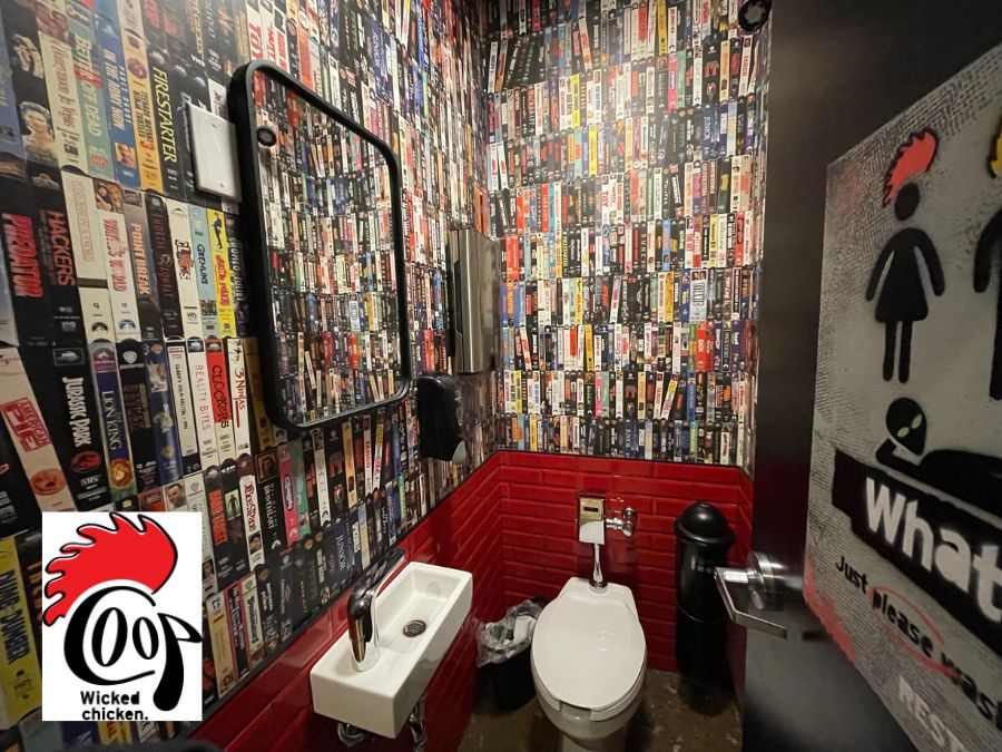Custom restaurant wallpaper, as seen on the walls of the Coop Wicked Chicken in Mississauga, ON, Canada, features stacked VHS tapes from the 80s and 90s creating a nostalgic look from About Murals.