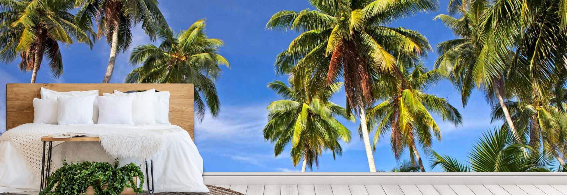 Summer wallpaper, as seen on the wall of a bedroom, is a photo wall mural of a tropical ocean scene with green trees from About Murals.